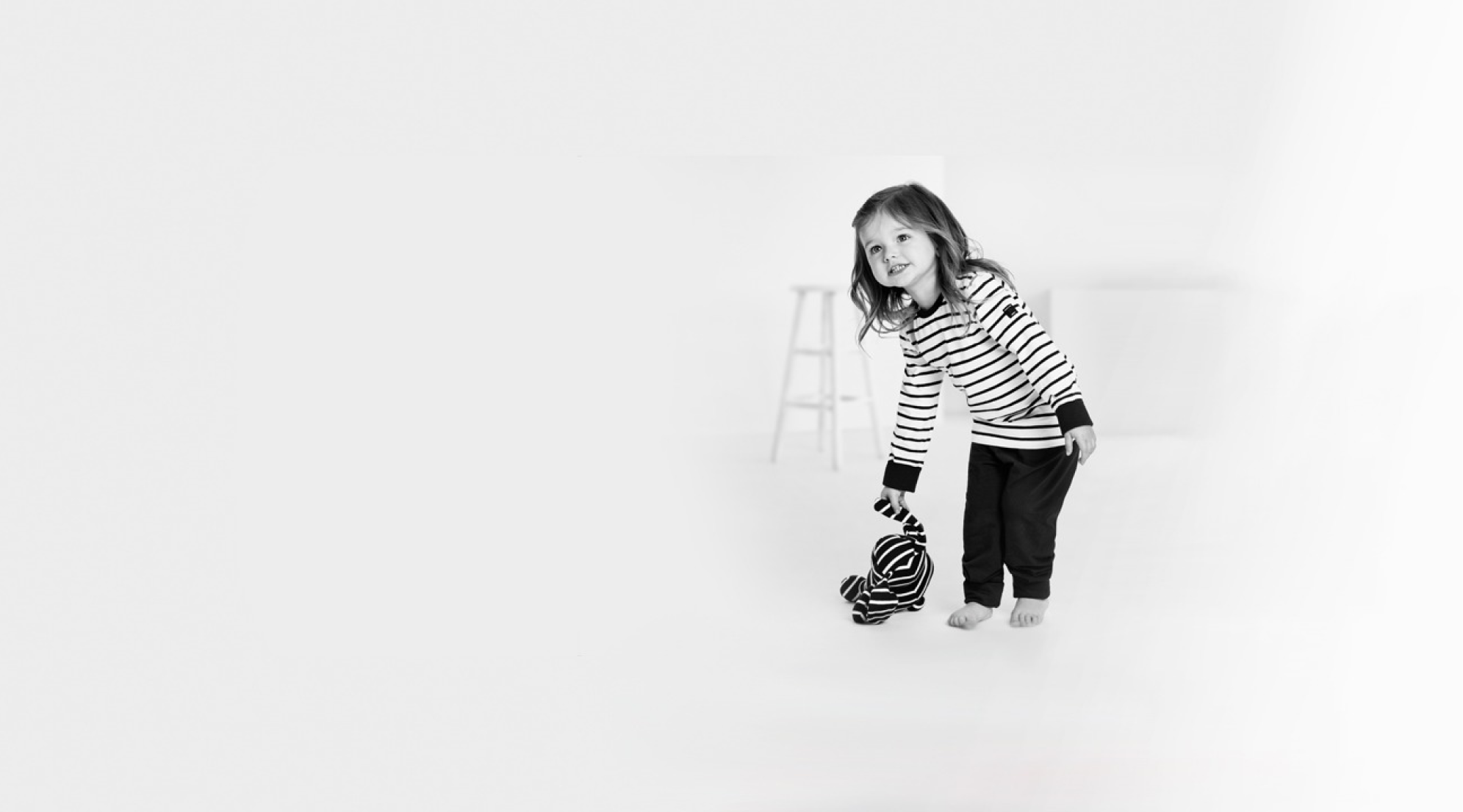 Smiling child in striped outfit standing in minimal studio setting