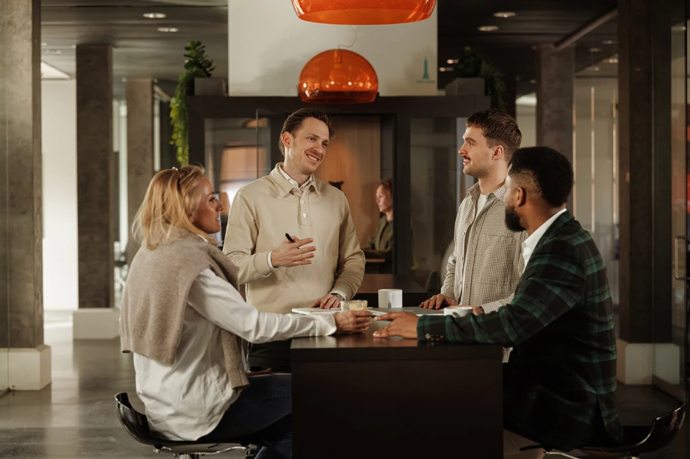 Four coworkers having a talk at a high table in an office
