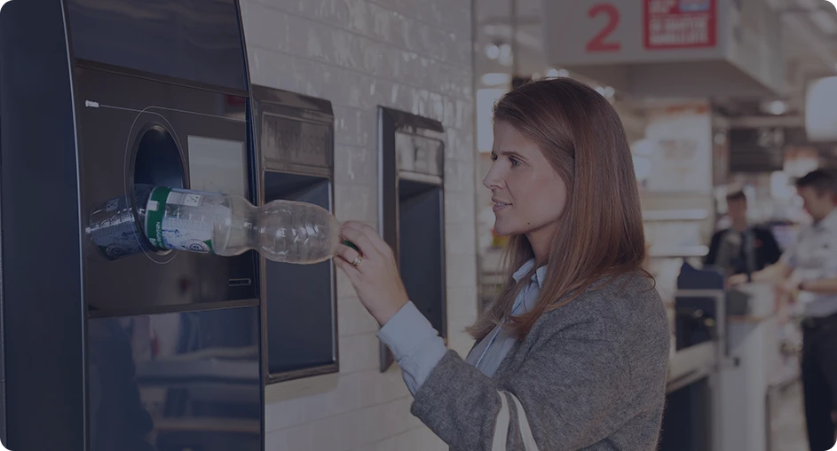 Customer recycling a plastic bottle at reverse vending machine
