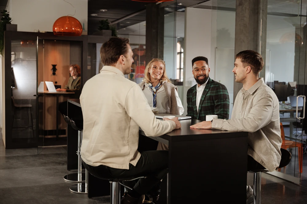 Coworkers in a conversation at a high table in their office