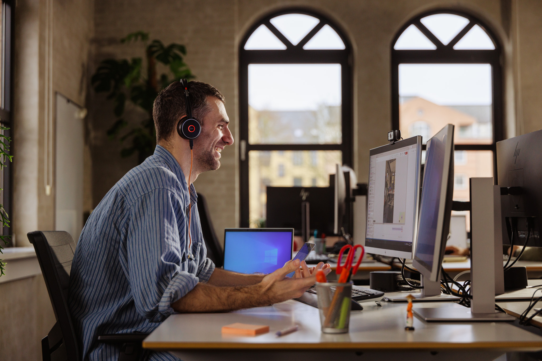 Man sitting at desk looking at computer wearing headphones smiling in a meeting