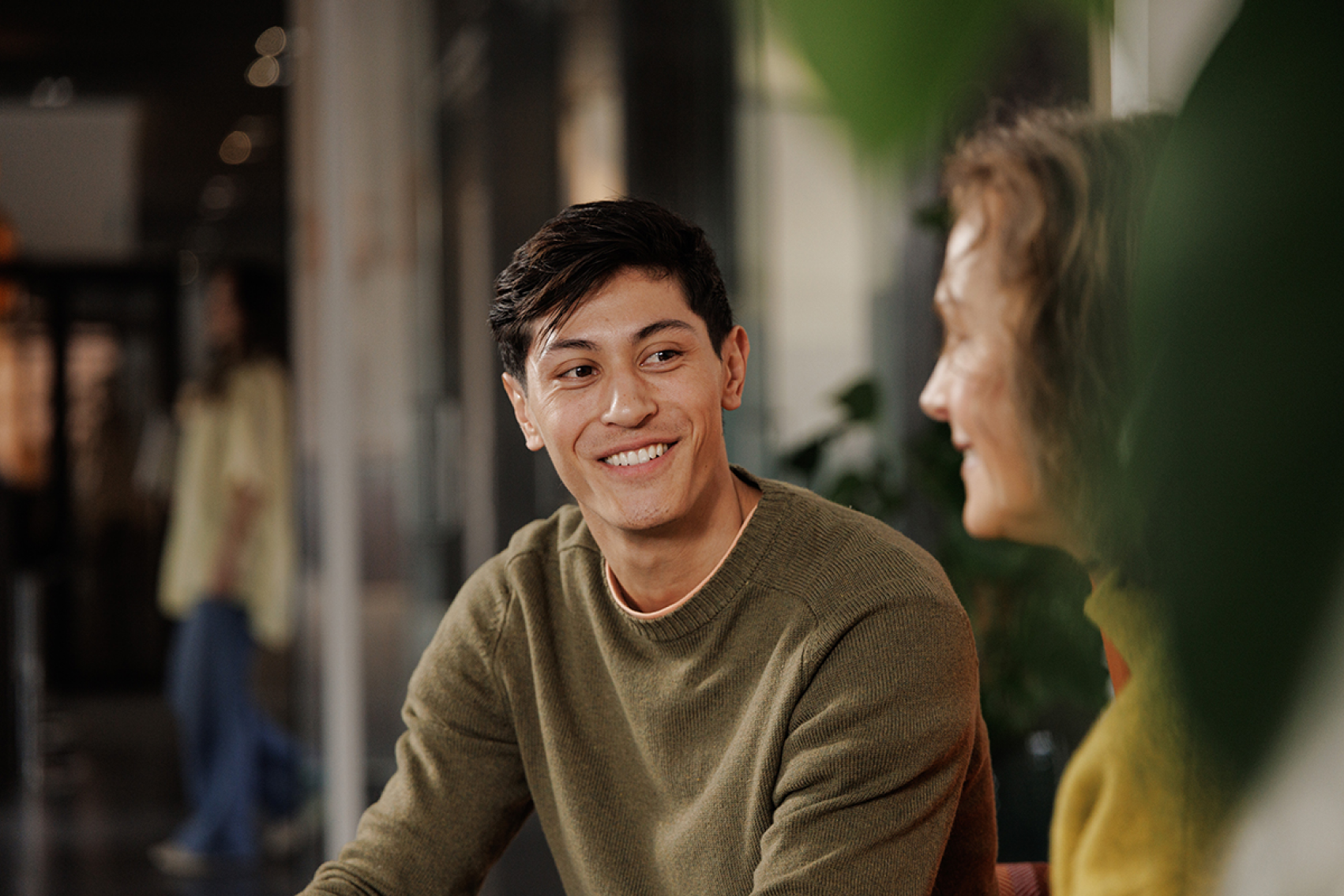 Young man in a sweater smiling at his manager while in a discussion